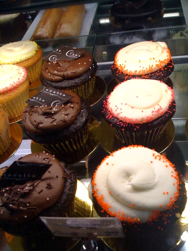 a bunch of assorted frosted cupcakes are on display