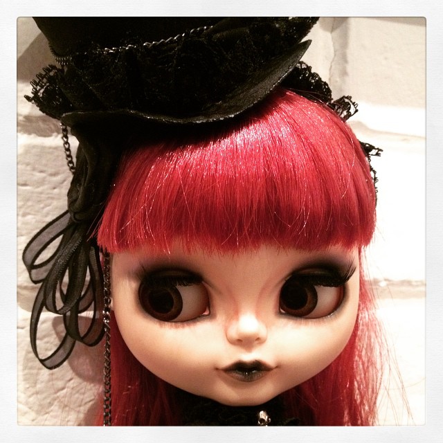 a close up of a doll with red hair and black dress