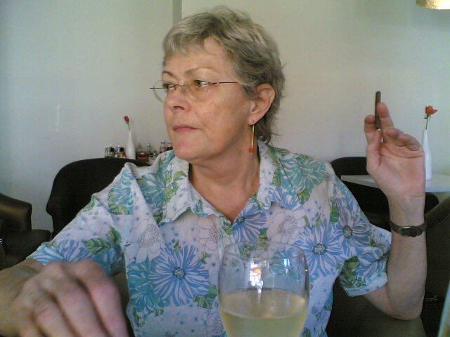 a woman is holding a glass of wine while smoking