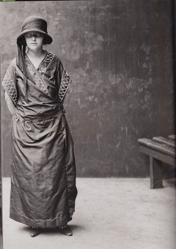 an old po of a woman standing in front of a wooden bench