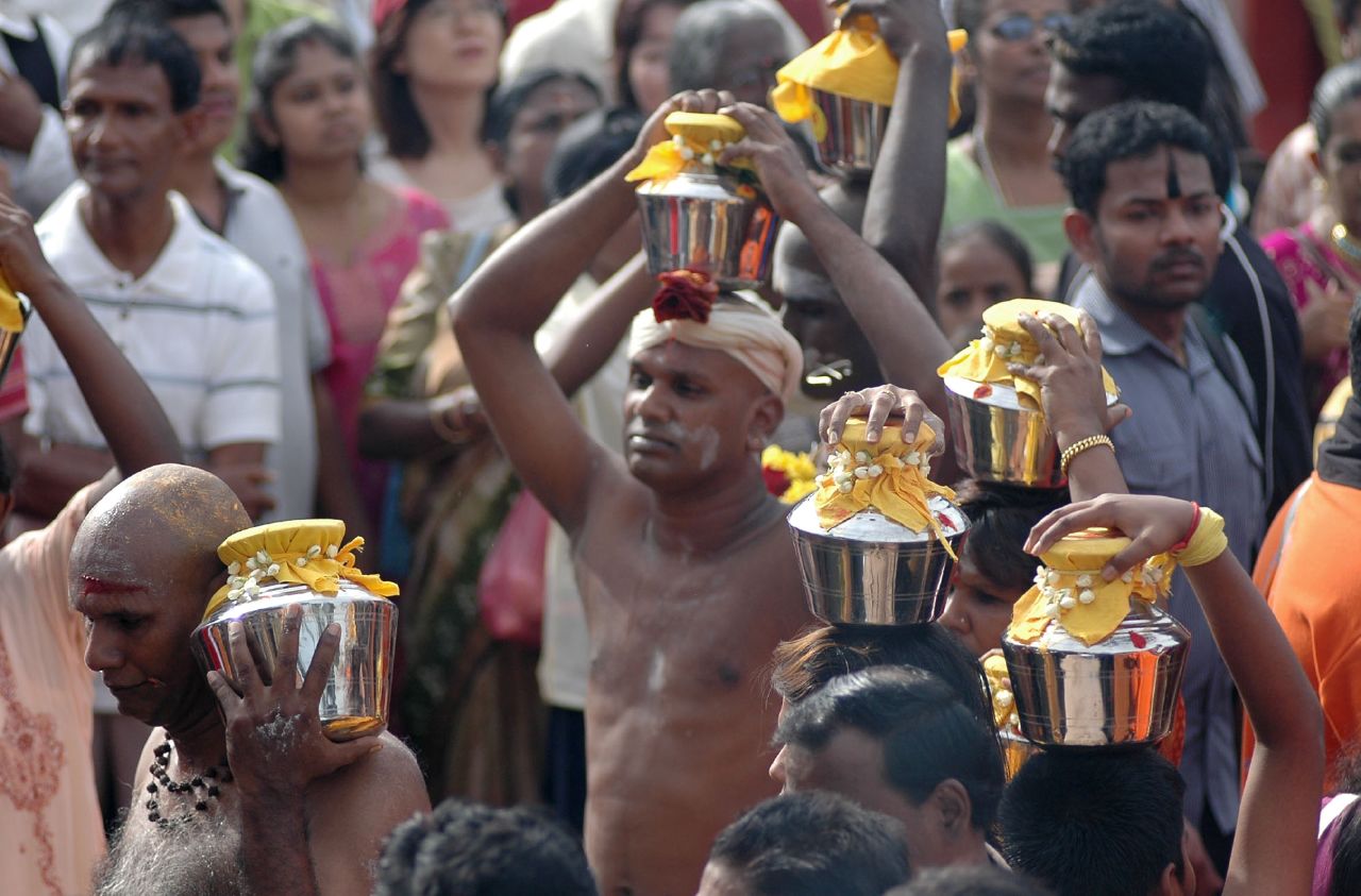 people at an indian festival with colorful hats and shiny golden cups