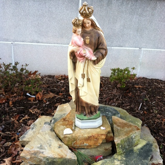 a statue of jesus holding a child in the garden