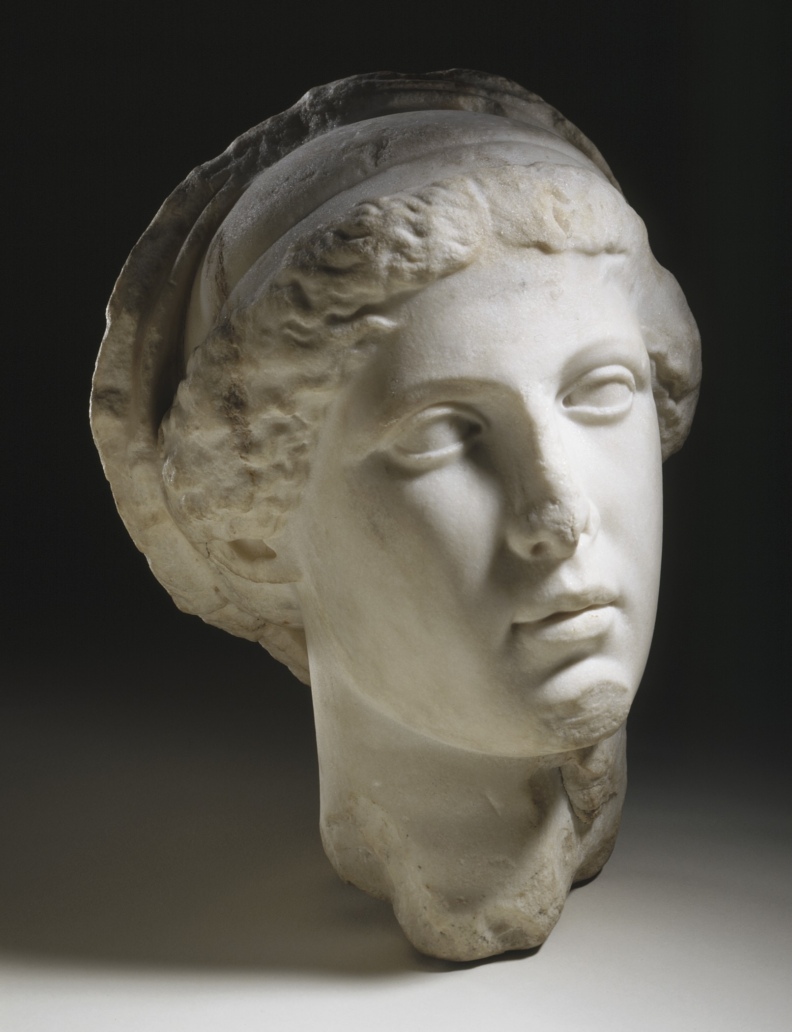 marble head of a woman with hair curled up on it's forehead