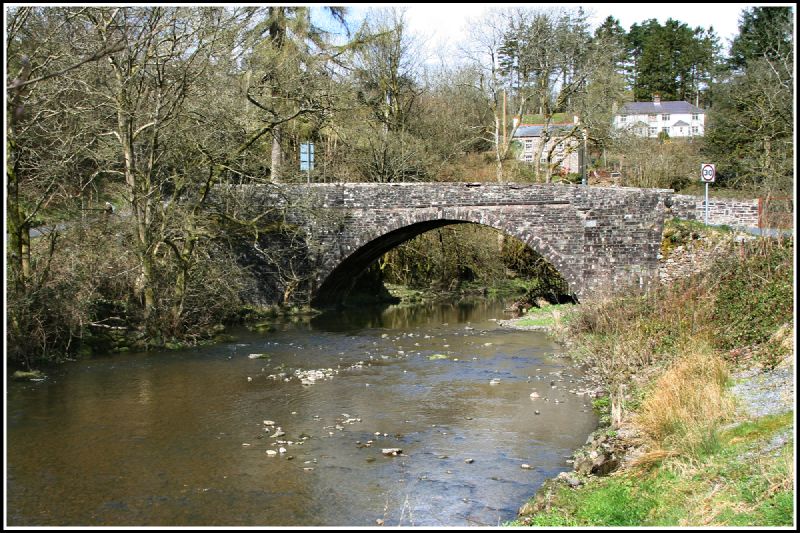 an old stone bridge over a river in the country side