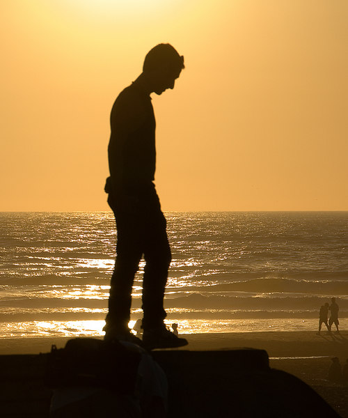 a person stands on their skateboard as the sun sets