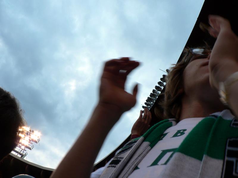 two fans wearing green and white watching some sports