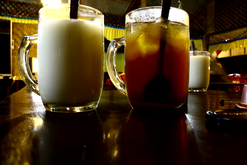 three drinks in tall glass mugs sit on a bar