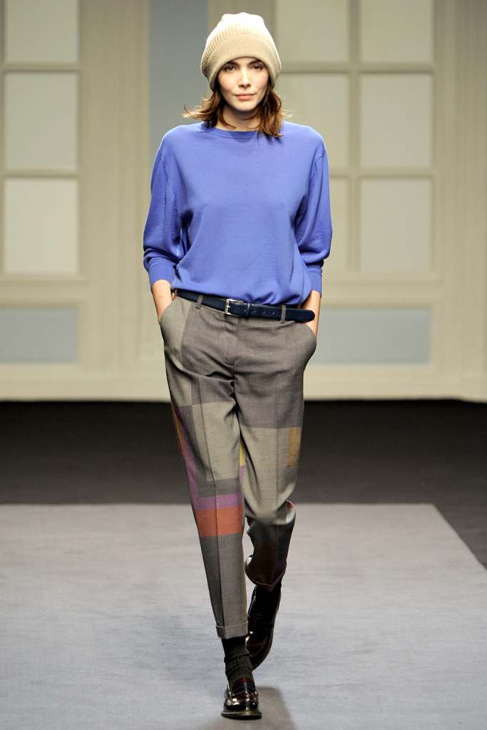 a woman in a blue shirt is walking on the runway