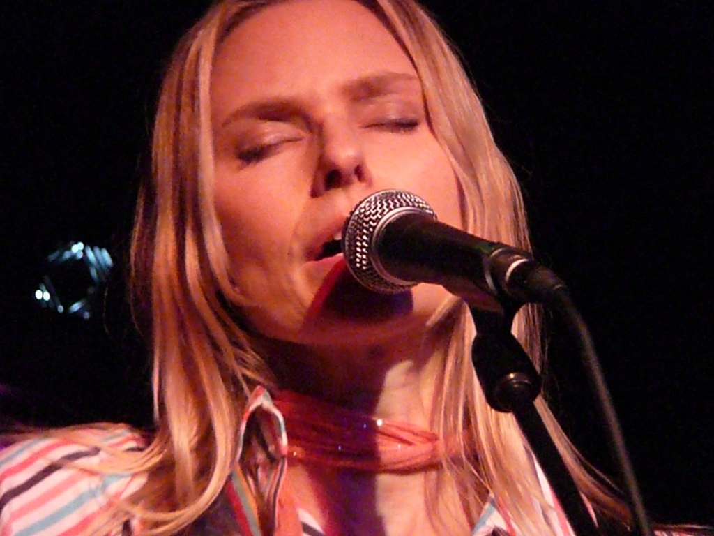 woman holding a microphone singing into her mouth