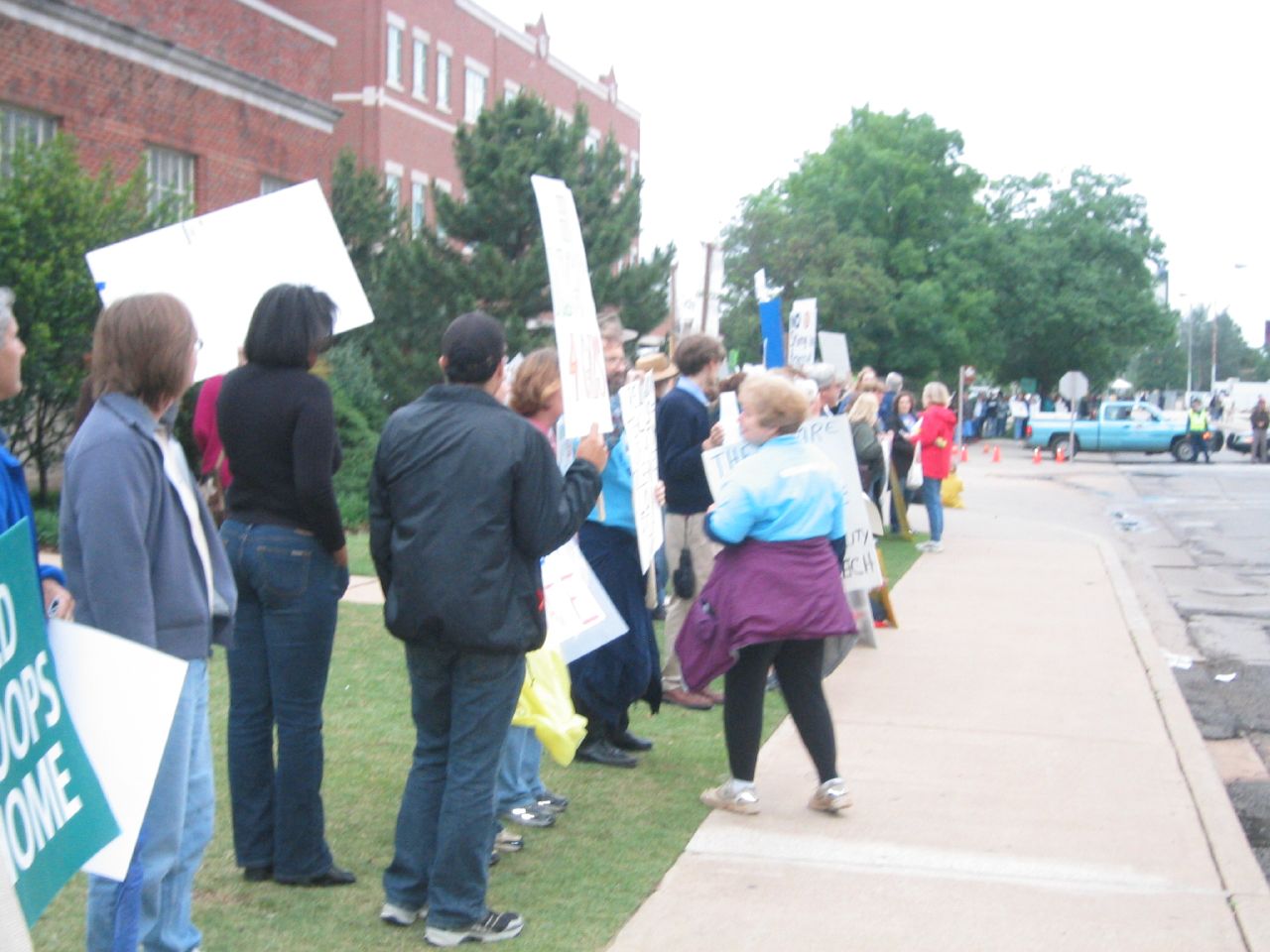 people hold signs and stand on a curb