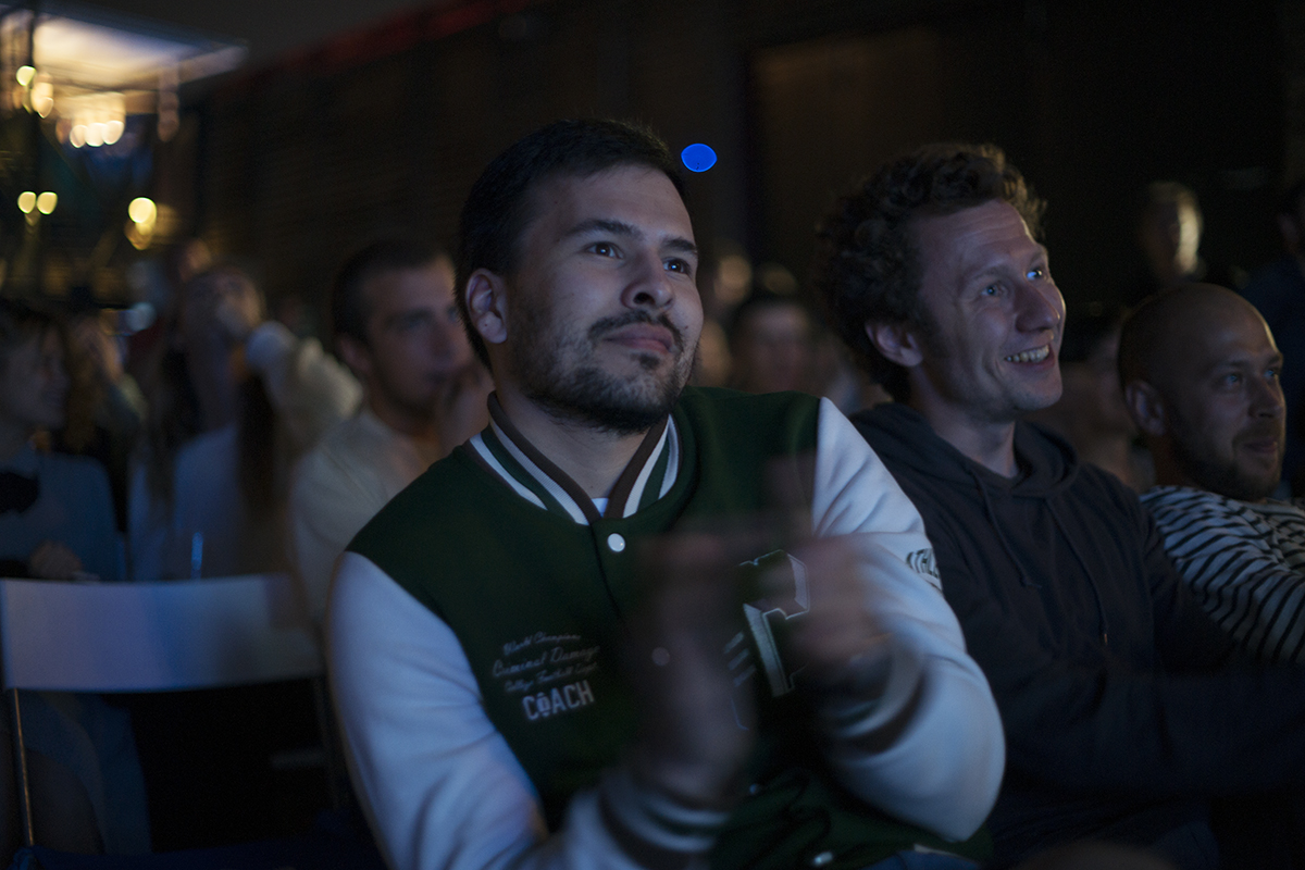 two men sitting at a table in front of a crowd