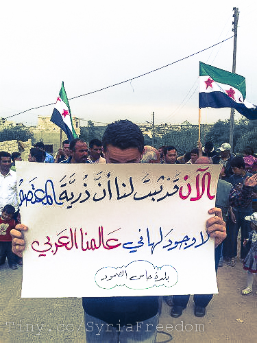a person with a white sign in arabic with a picture of a man holding a flag on the side