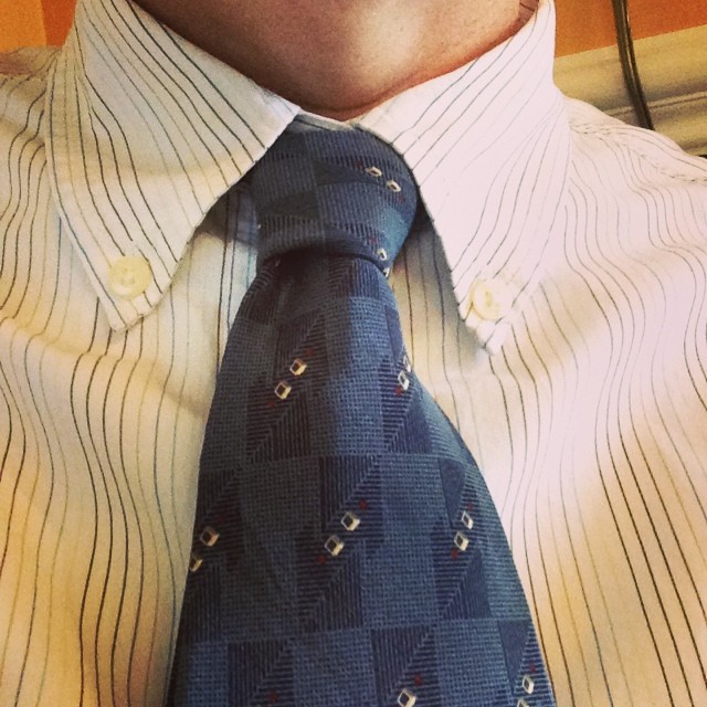 a closeup of a man wearing a blue tie and dress shirt