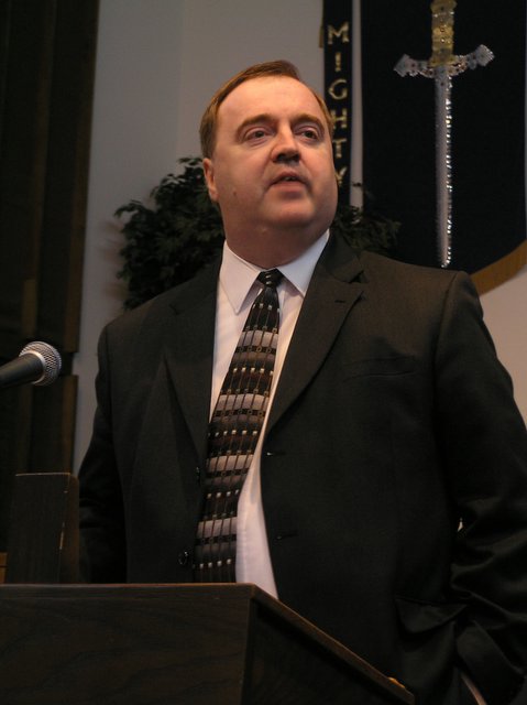 a man in a suit stands behind a podium as he speaks into the microphone