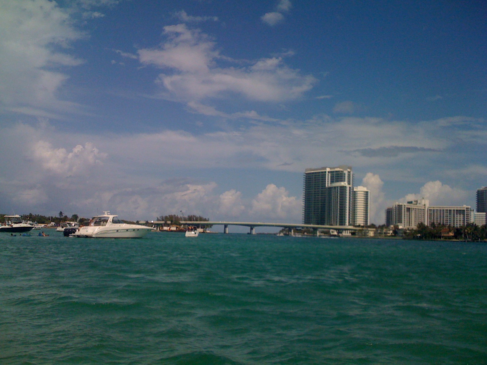 a boat is in the water by a bridge and some buildings