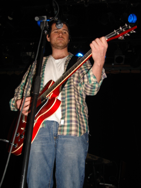 a man with sunglasses on, playing guitar at a concert