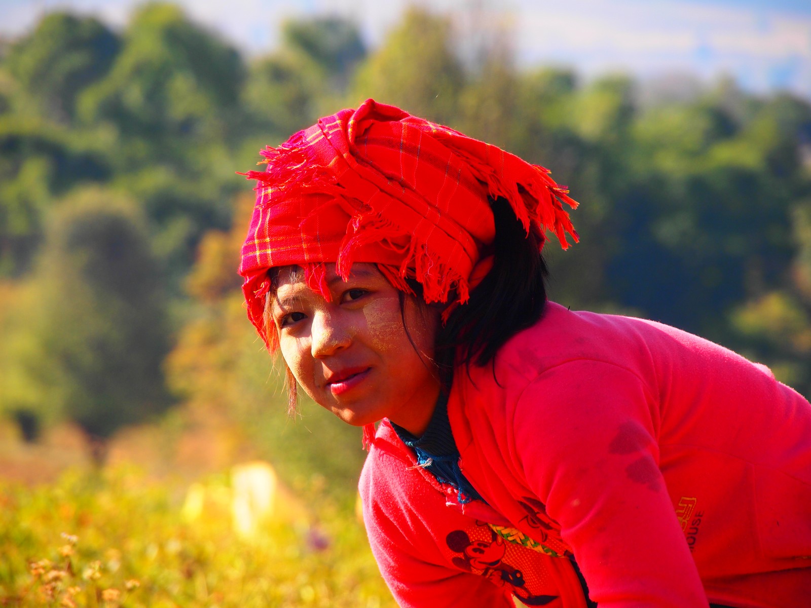 a woman in a red cloth sits in a grassy field