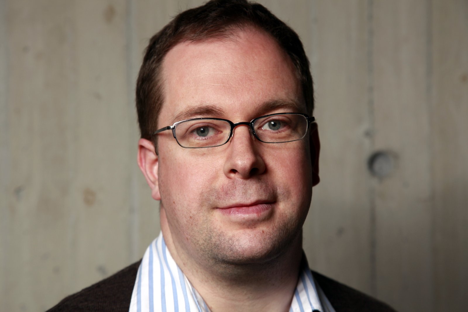 a man with glasses and striped shirt poses for a po