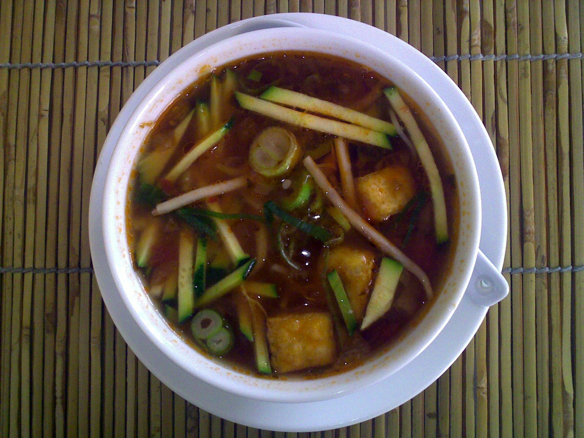 a bowl of soup containing vegetables and sauce