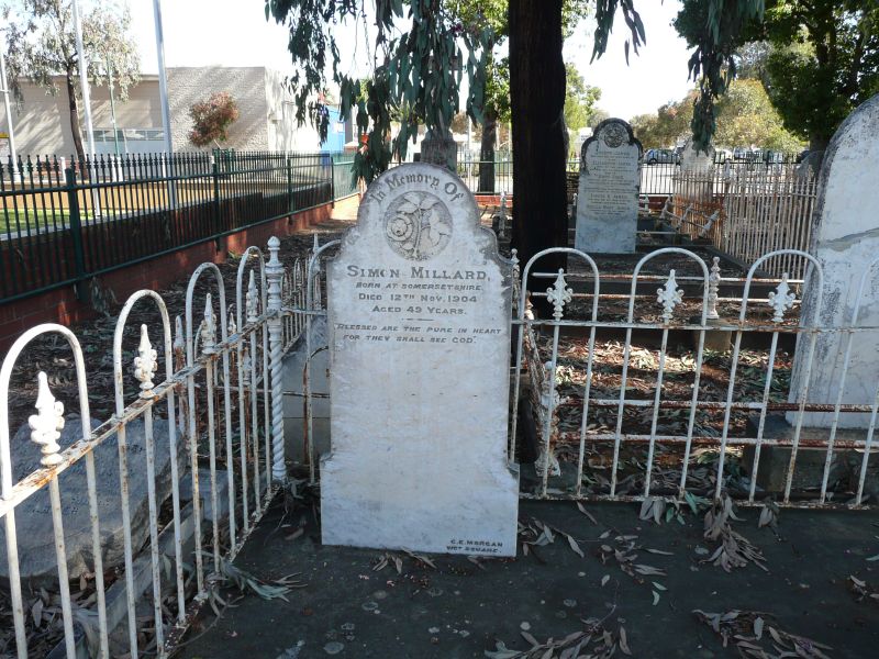 the gate to a cemetery is open and has a white headstone in it