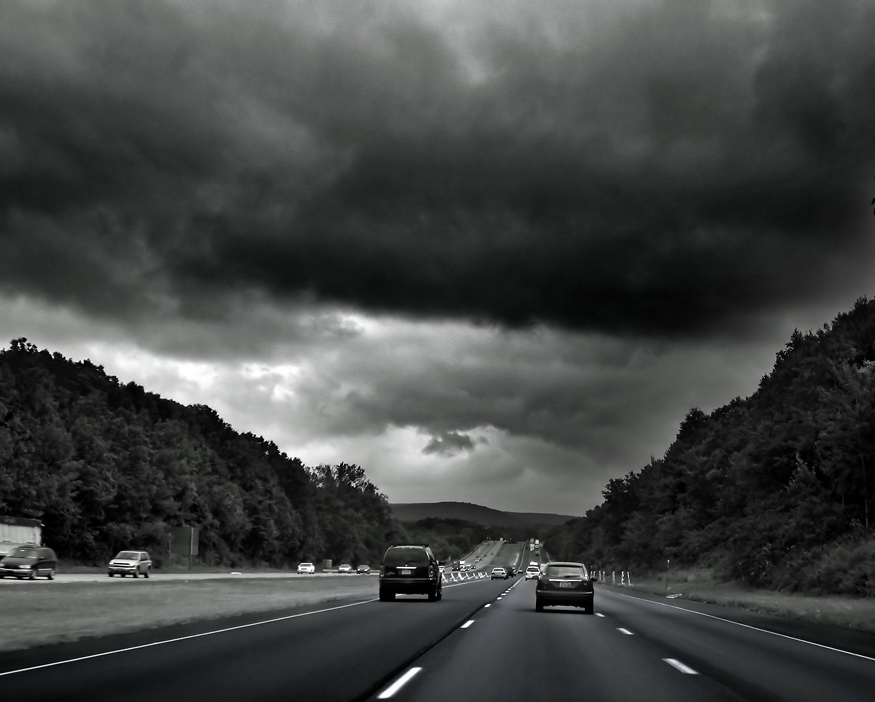 a cloudy day over several cars travelling on the road