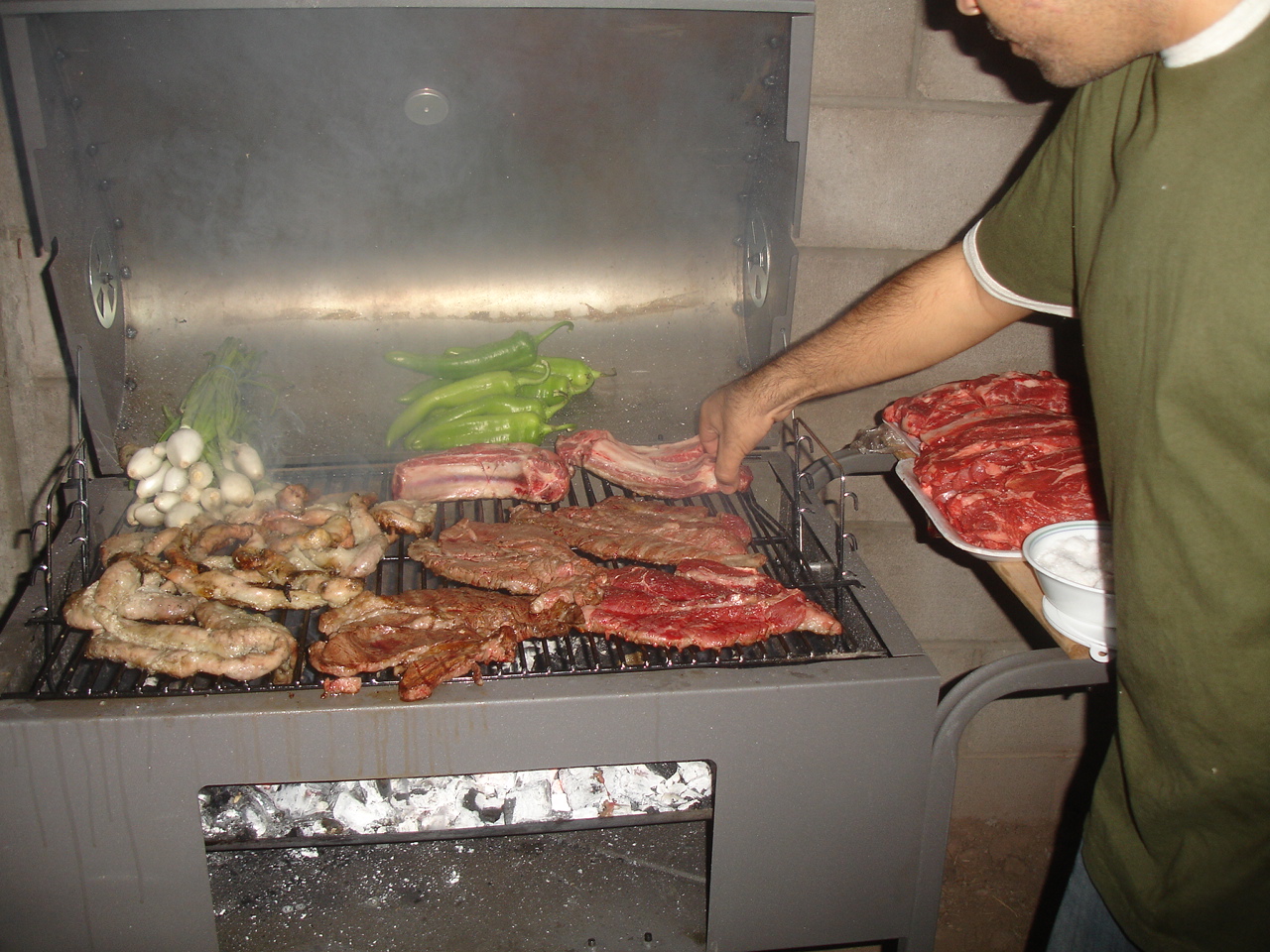 man cooking meats and other foods on a grill
