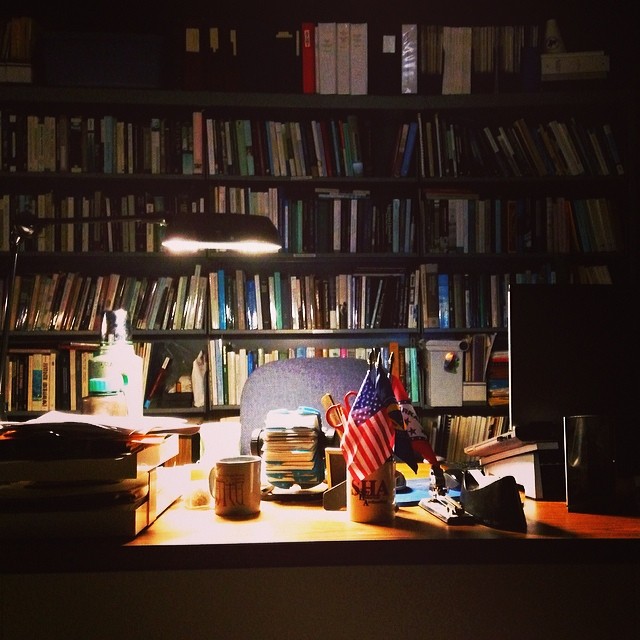 an office desk with computers and bookshelves in the background