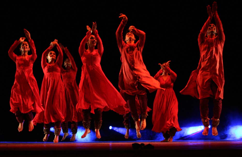 people wearing red dance on stage in long dresses