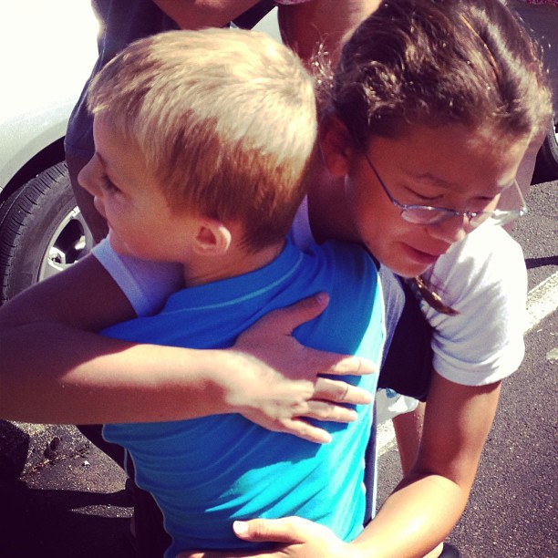 two boys hugging each other in front of a car