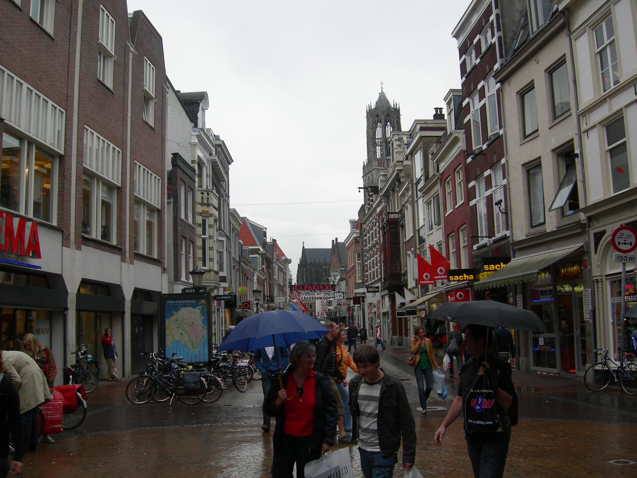 people walk down a street with umbrellas in the rain