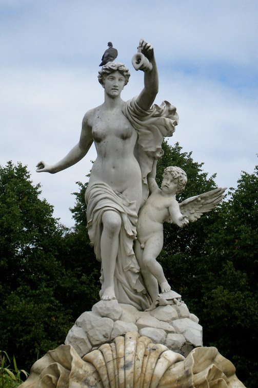 a statue of an angel holding a baby next to a seashell