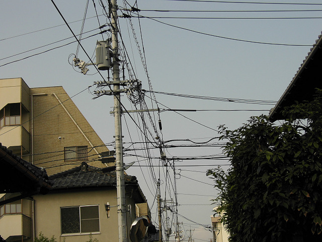 a telephone pole with wires above it and houses nearby