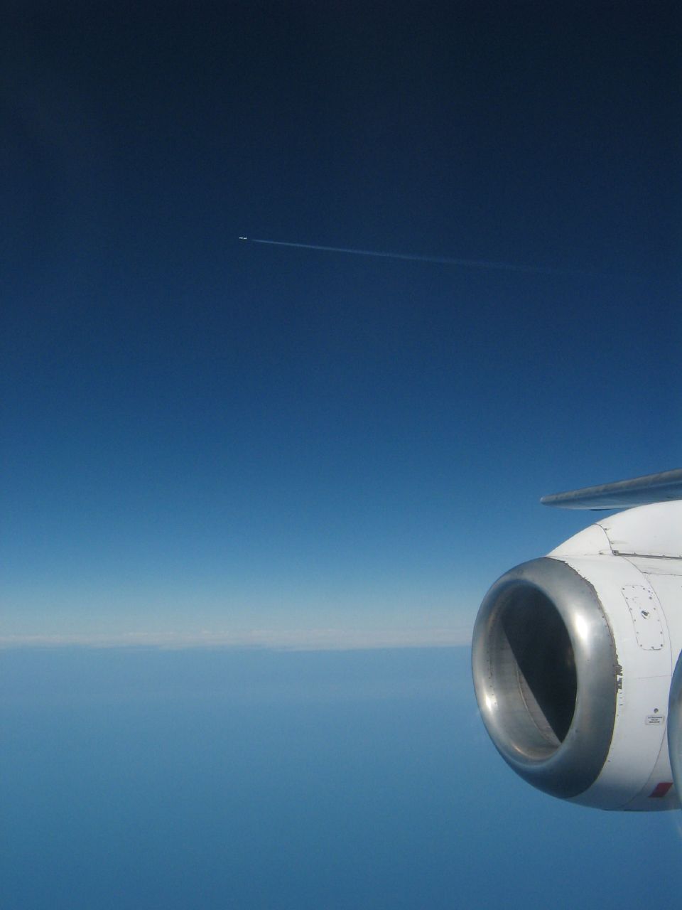 a plane wing flying over the ocean and a blue sky