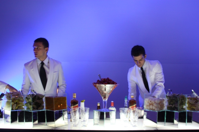 a couple of men standing behind table with drinks