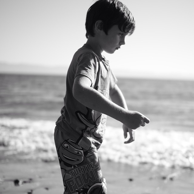 a black and white po of a boy on the beach playing with a surfboard