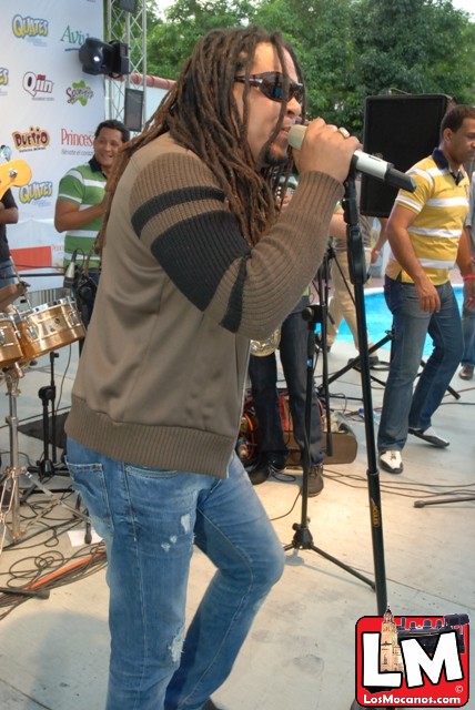 a man with dreadlocks standing next to a microphone