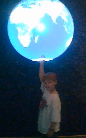 a  holds up an illuminated globe in the dark