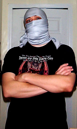 a man in a black shirt with a mask on and his arms crossed