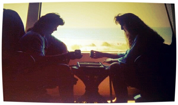 two people sit at a table next to an ocean