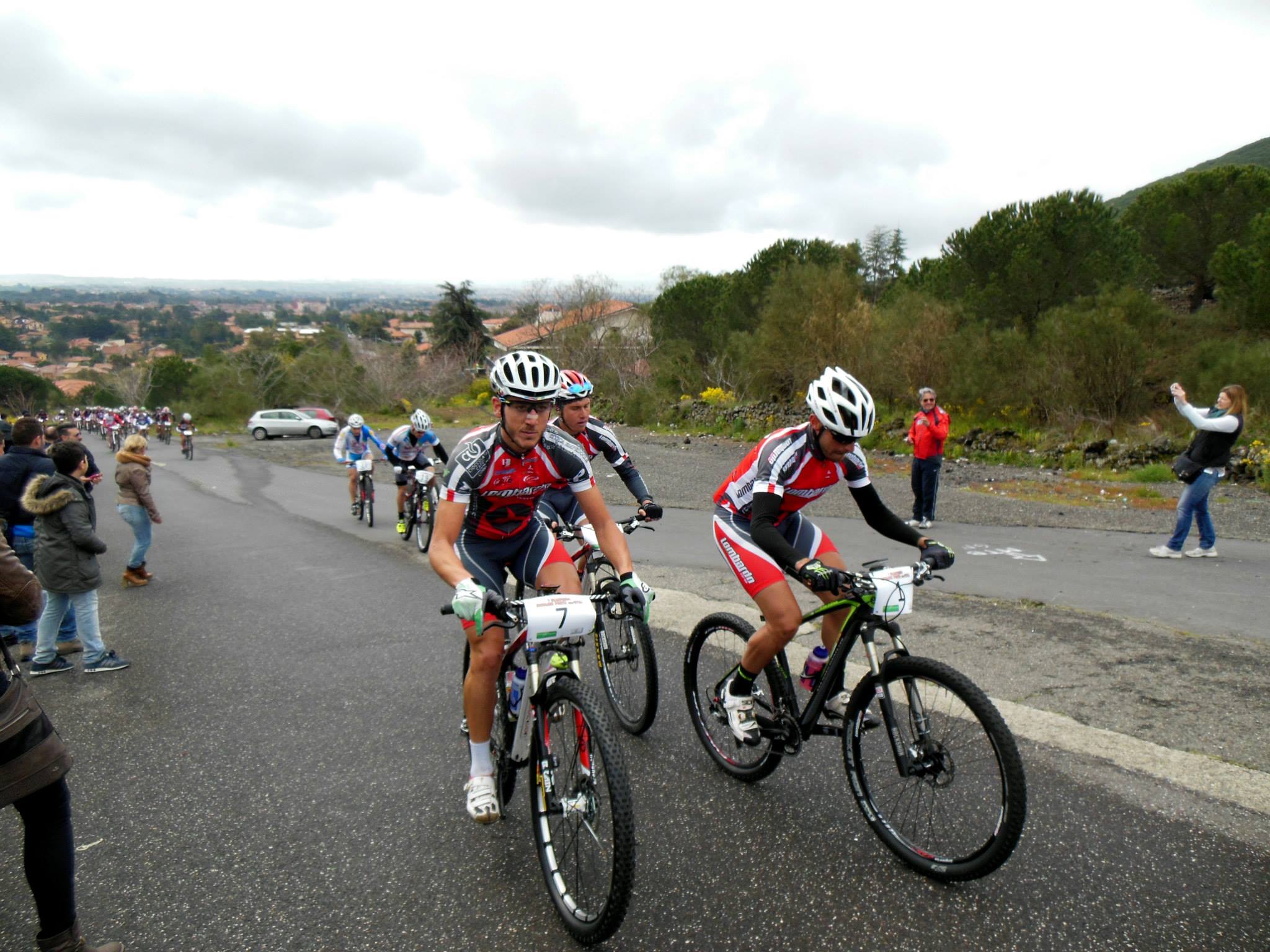 two people riding bikes on the side of a road