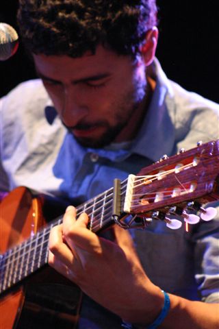 a man playing the guitar on stage at a concert