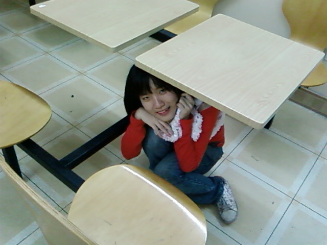 a girl sitting on the ground in a desk - like area