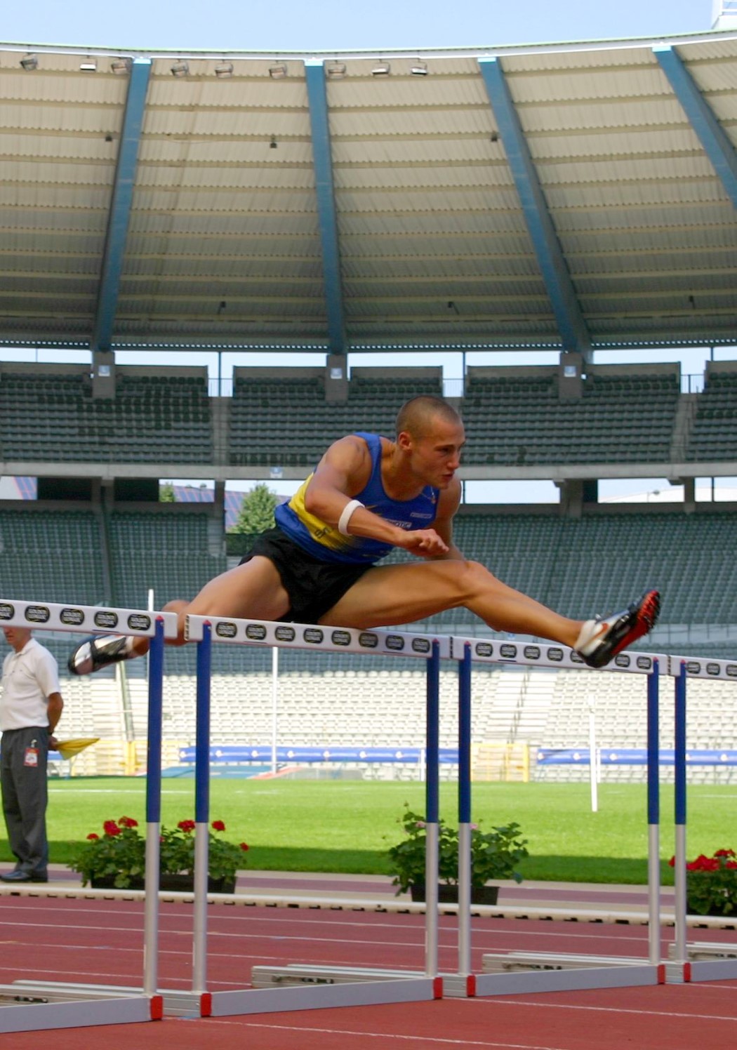 an athlete leaps over an obstacle in an athletics stadium