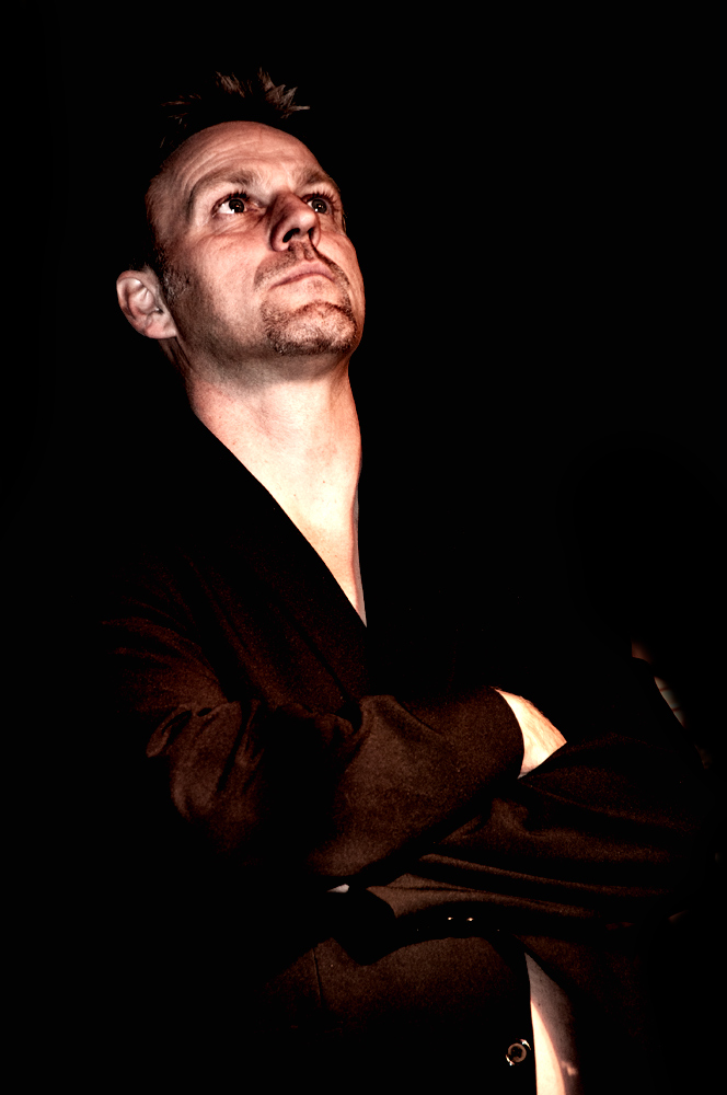 man with crossed arms posing for picture in dark background