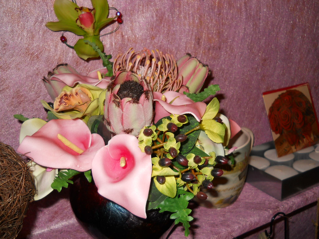 a black vase filled with different colored flowers on a pink surface