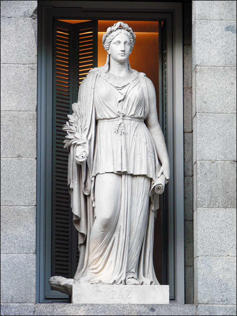 a statue of a woman standing next to a wall