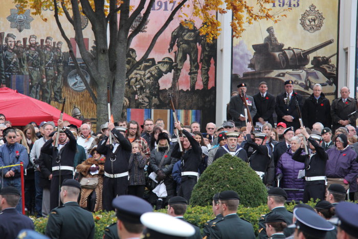 a large group of people watching men in uniform in front of a crowd