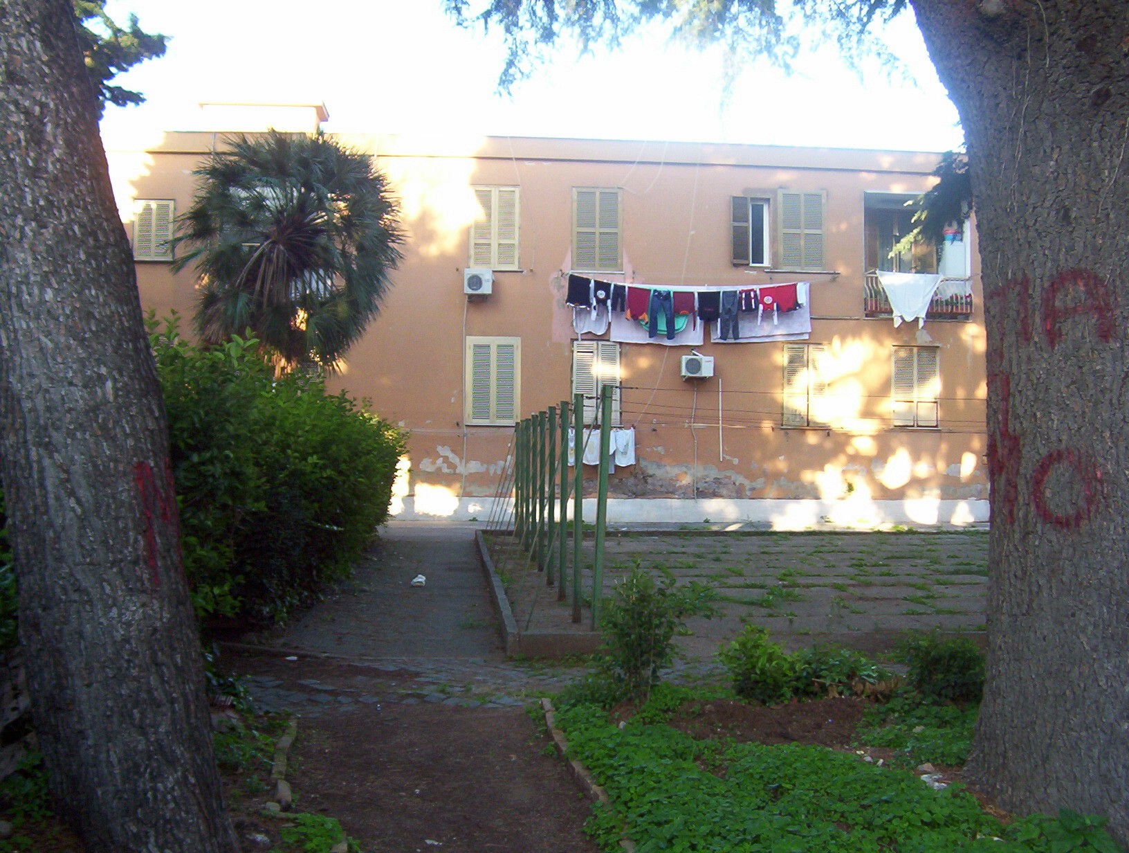 trees are next to a path leading up towards a building with laundry hung on a clothes line