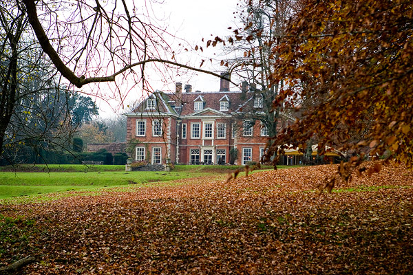 a large house is near some trees with autumn leaves on the ground