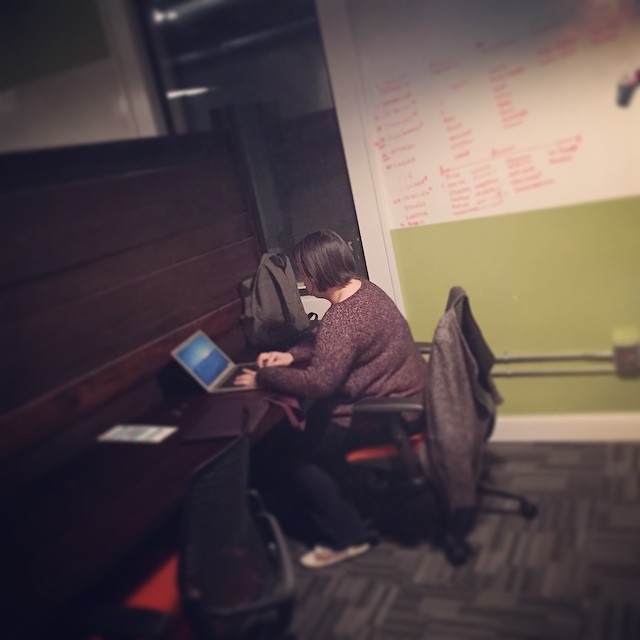 woman sitting down using laptop in small room